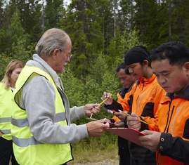 Alf Hallén delar ut formulär till skogsarbetare.