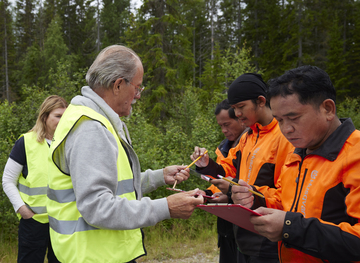 Alf Hallén delar ut formulär till skogsarbetare.